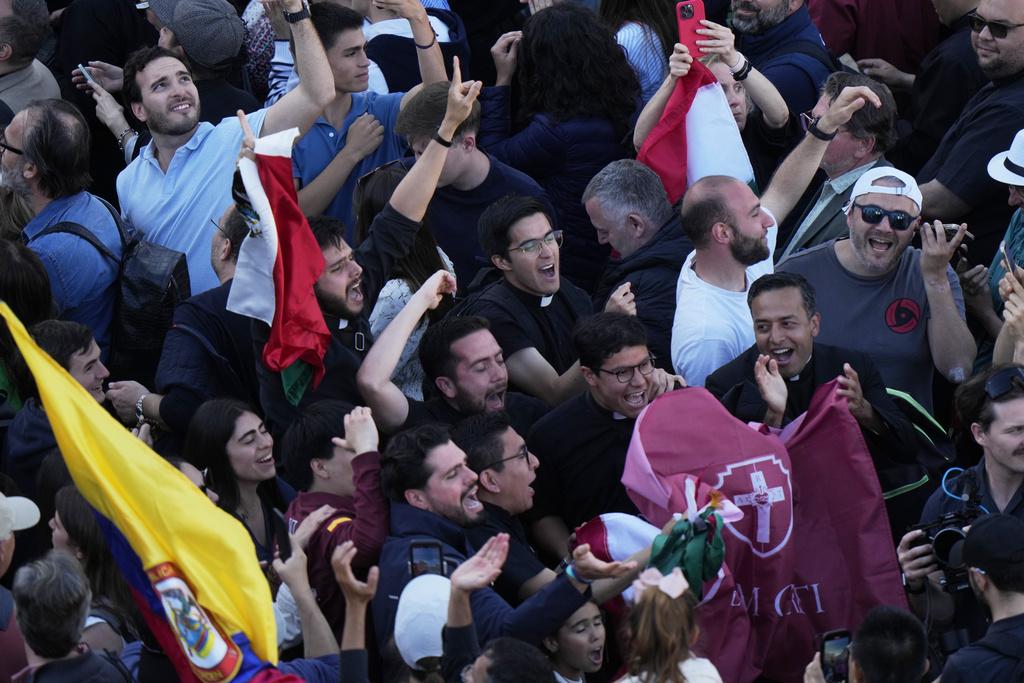 People react as white smoke billows from the chimney of the Sistine Chapel where 133 cardinals are gathering on the second day of the conclave to elect a successor to late Pope Francis