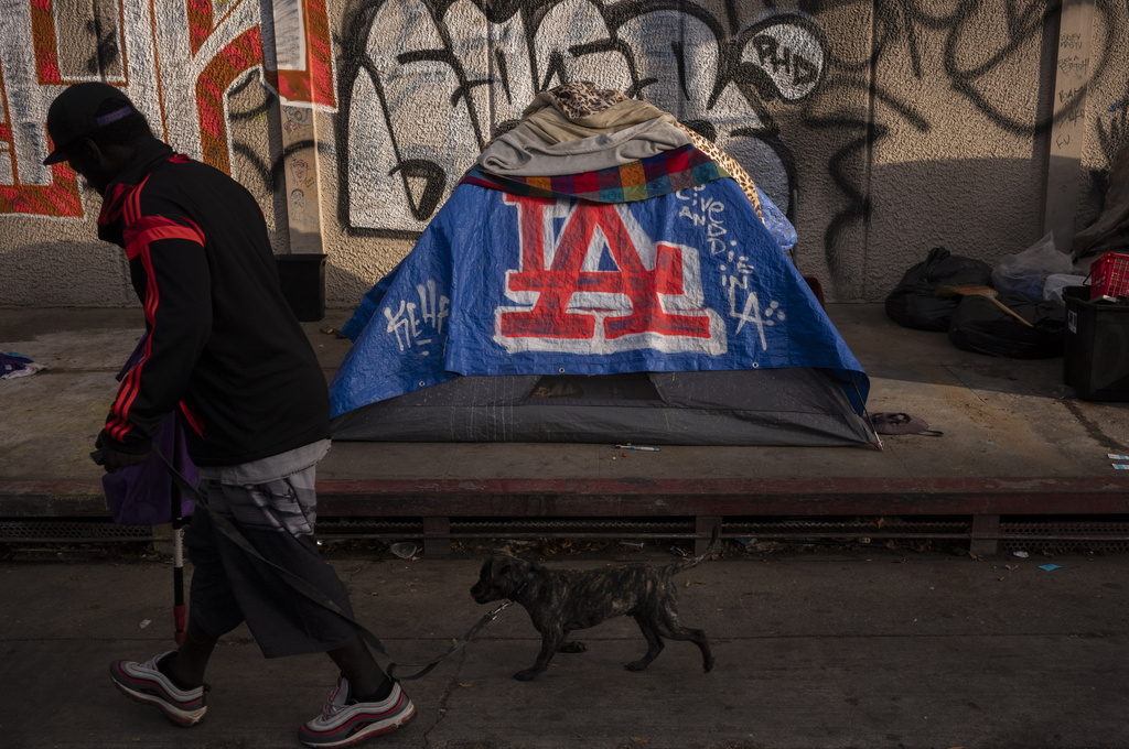 A man walks past a homeless encampment in downtown Los Angeles