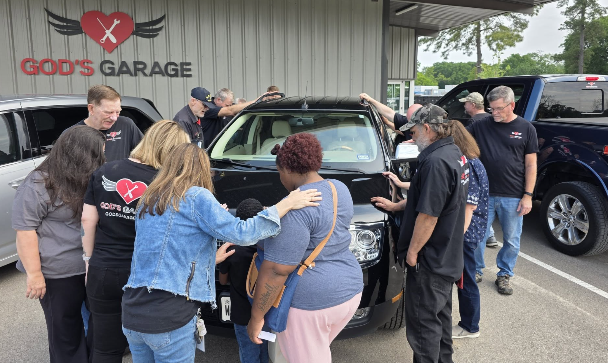 Volunteers and single mom praying over car